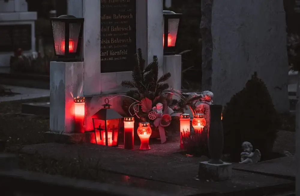 Lanterns and candles glowing at a family monument at dusk