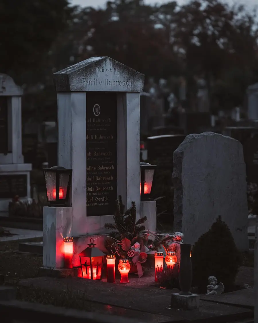 Lanterns and candles glowing at a family monument at dusk